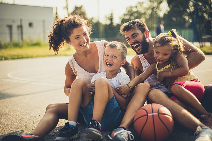 Employee Benefits - Portrait of Family with Two Children After Playing Basketball at a Playground